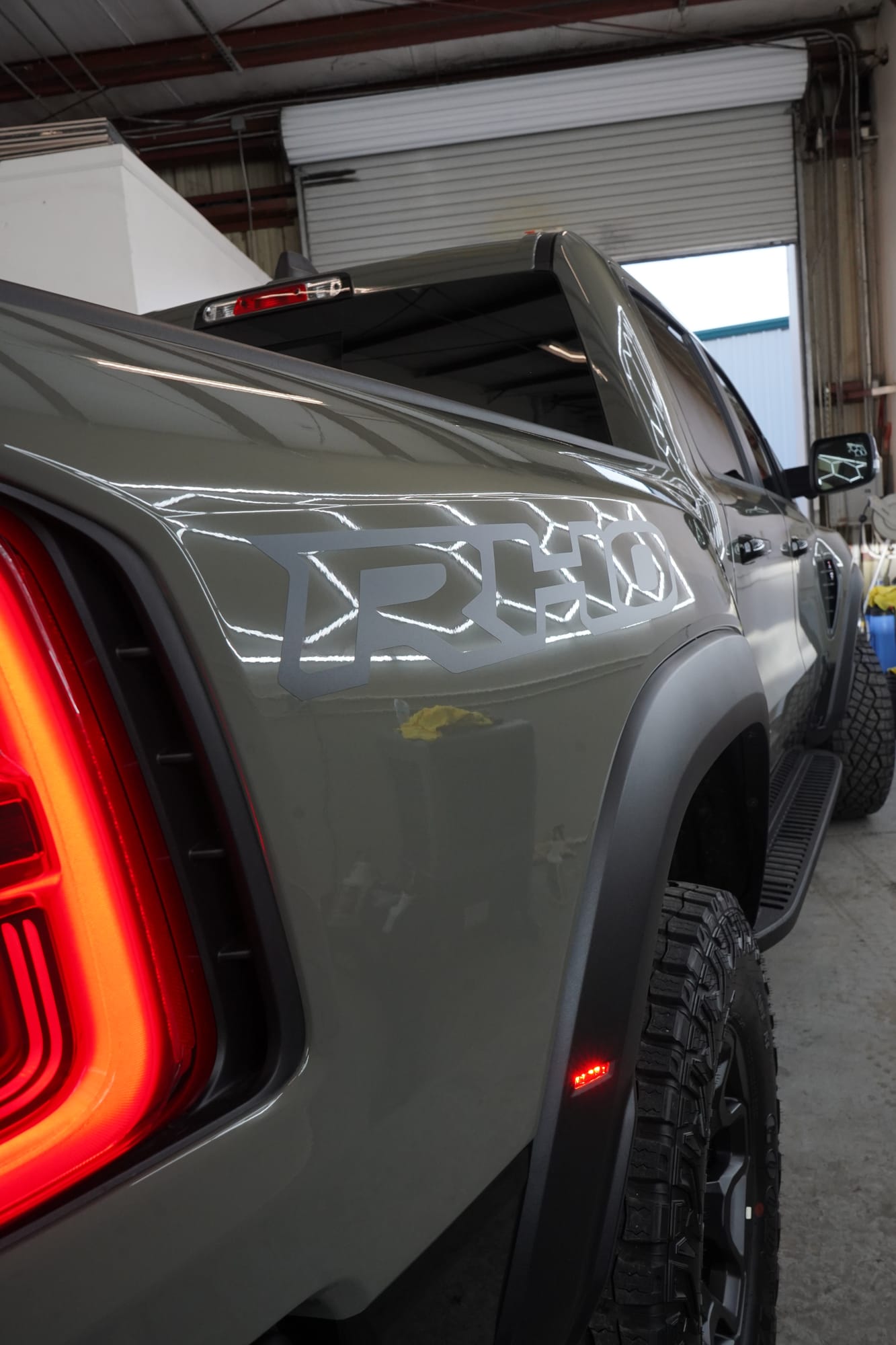Taillight and bed of a Ram RHO after a ceramic coating, the shop lights reflected in the paint